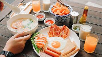Una mesa con un plato que incluye sopa, tocino, huevos y verduras.