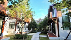 A courtyard with two-story buildings, a central pathway, and surrounding greenery. - Baanrongmai Canal Front Homestay (Phra Pradaeng)