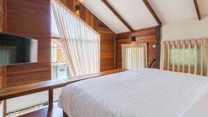 A bedroom with a large bed, wooden paneling, a flat-screen TV, and large windows with curtains. - Baanrongmai Canal Front Homestay (Phra Pradaeng)