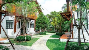 A courtyard with a pathway, wooden structures, and greenery. - Baanrongmai Canal Front Homestay (Phra Pradaeng)