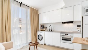 Uma cozinha moderna com armários brancos, forno embutido e máquina de café.