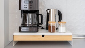 Uma cozinha moderna com uma cafeteira, um bule e dois potes de especiarias em uma bancada.