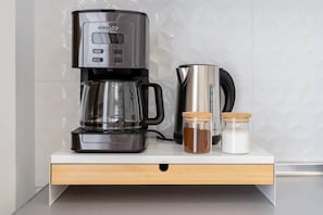A modern kitchen with a coffee maker, a kettle, and two jars of spices on a countertop. - Light Brisa Apartment (Fuengirola)