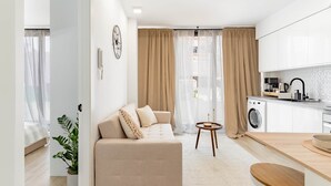Apartamento moderno com sala de estar, cozinha compacta e máquina de lavar.