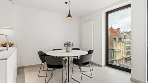 A modern dining area with a round table, black chairs, and a vase of flowers. - Beautiful apartment in the center (Blankenberge)