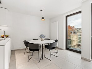 A modern dining area with a round table, black chairs, and a vase of flowers. - Beautiful apartment in the center (Blankenberge)