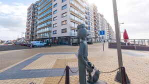 Ein modernes Apartmenthaus mit mehreren Balkonen und einer Statue im Vordergrund.