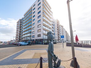 Ein modernes Apartmenthaus mit mehreren Balkonen und einer Statue im Vordergrund.