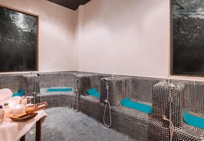 Une salle de spa dotée d’un espace détente avec des motifs décoratifs, d’une table de massage et d’une petite table ornée de bougies et de bouteilles.