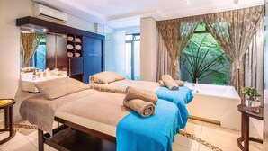 Habitación de hotel con dos camas, una bañera, un tocador con espejo y una ventana con cortinas.