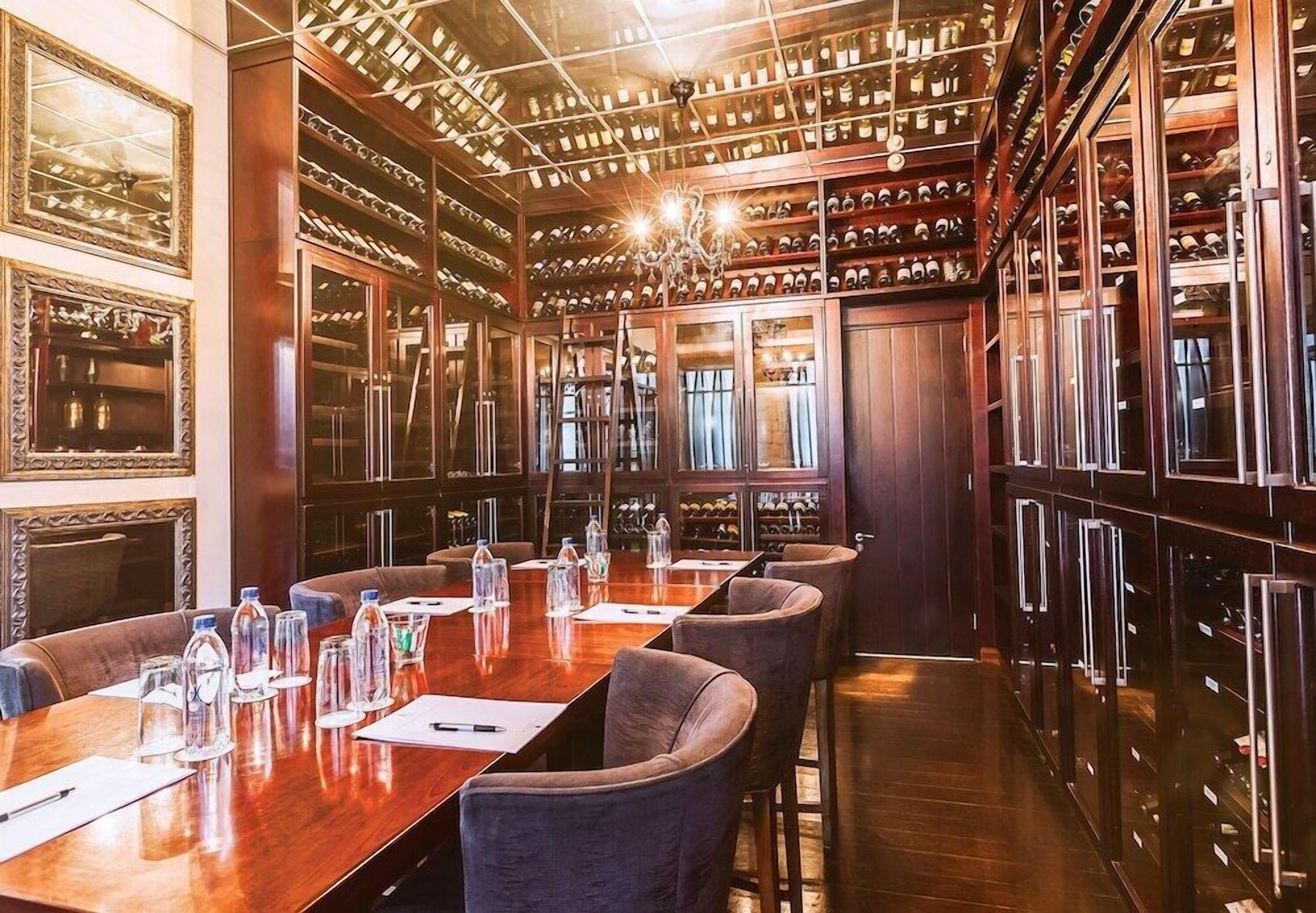 A conference room with a long table, chairs, and a wine rack along the wall.