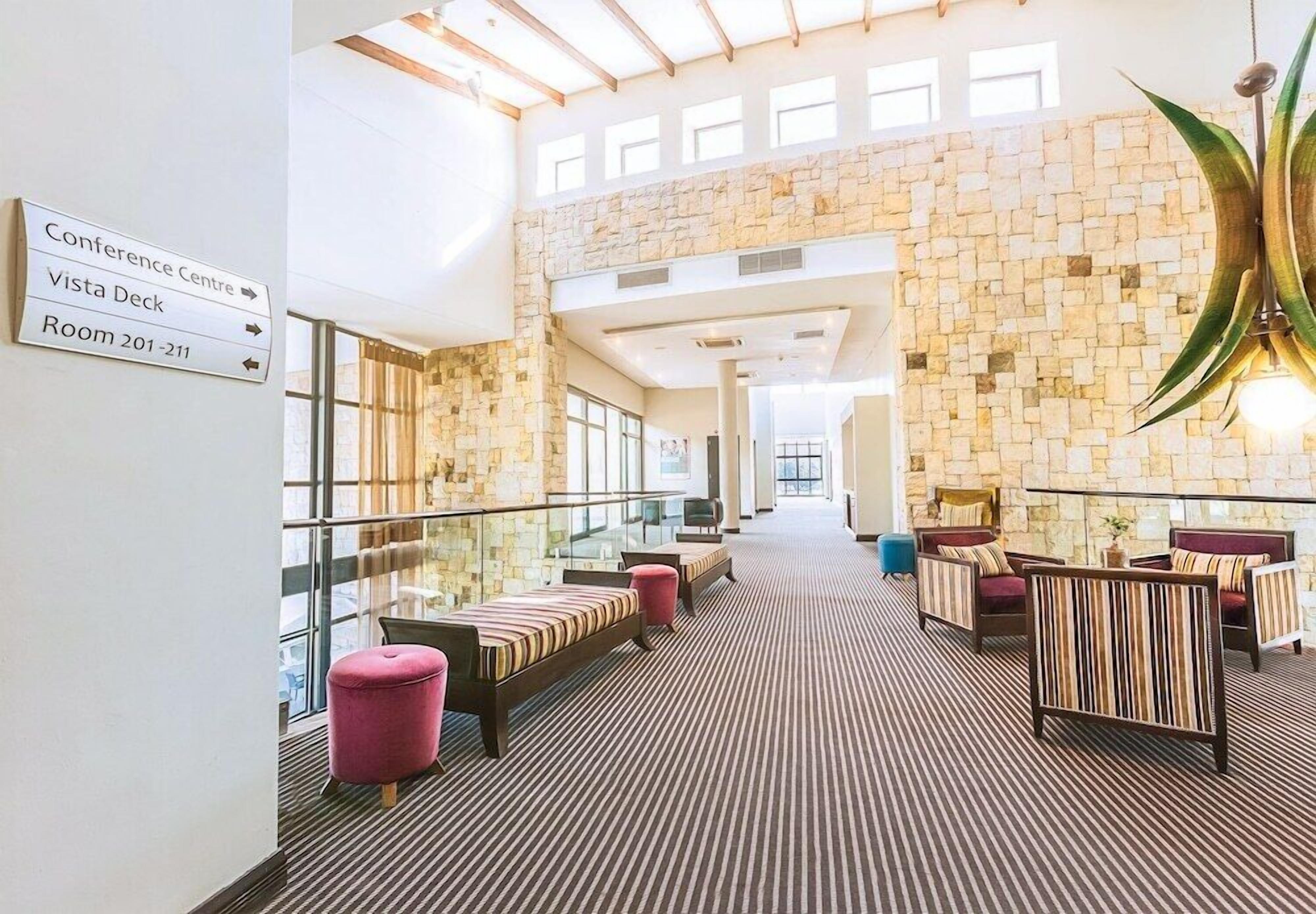 A hotel lobby with a stone wall, seating area, and directional signs.