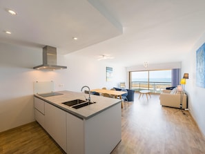 Eine moderne Küche mit Kochinsel, ein Essbereich mit Aussicht und ein Wohnbereich mit Balkon.