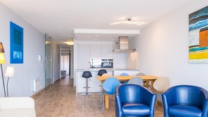 A modern living room with a sofa, a dining table with chairs, and a kitchen in the background. - Modern apartment with direct sea view (Middelkerke)