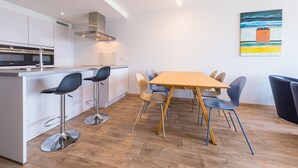 A modern kitchen with a central island, bar stools, and a dining table with chairs. - Modern apartment with direct sea view (Middelkerke)