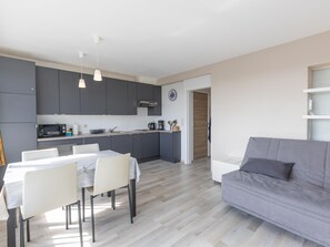A modern kitchen with grey cabinets, a dining table with chairs, and a grey sofa in a living area. - Studio on the 5th floor with a beautiful view (Middelkerke)
