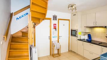 A kitchen with a wooden staircase, a microwave, a coffee maker, and a sink.