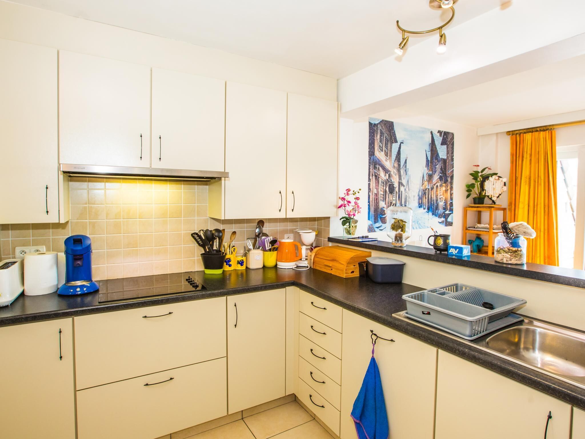 A modern kitchen with white cabinets, a black countertop, and various kitchen appliances.