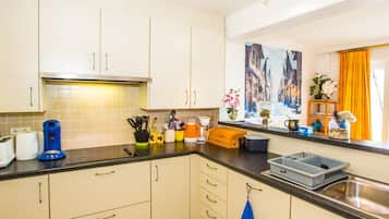A modern kitchen with white cabinets, a black countertop, and various kitchen appliances.