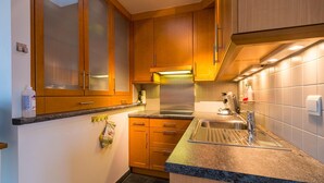 Una cocina compacta con armarios de madera, un lavamanos de acero inoxidable y encimera de granito.