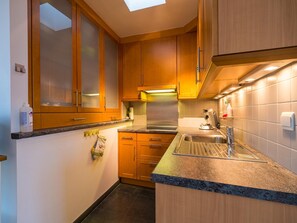 A compact kitchen with wooden cabinets, a stainless steel sink, and a granite countertop. - Duplex apartment near the sea (Middelkerke)