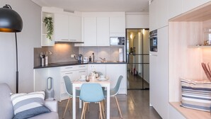 Eine moderne Küche mit weißen Schränken, einem Essbereich mit Tisch und Stühlen sowie einem eingebauten Backofen.