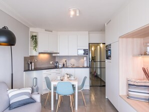 Eine moderne Küche mit weißen Schränken, einem Essbereich mit Tisch und Stühlen sowie einem eingebauten Backofen.