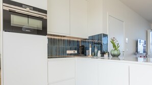 A modern kitchen with white cabinetry, a built-in oven, and a coffee maker. - Exclusive penthouse with breathtaking 360° view (Middelkerke)
