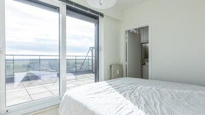 A bedroom with a large window, a bed, and a view of a cityscape. - Exclusive penthouse with breathtaking 360° view (Middelkerke)
