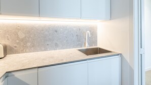 Une cuisine moderne dotée d’un plan de travail en granit, d’un évier en acier inoxydable et de meubles blancs.