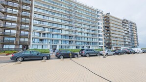 Um hotel moderno de vários andares com fachada uniforme, área de estacionamento com vários carros e céu limpo.