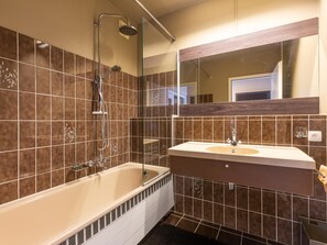 Ein modernes Badezimmer mit Badewanne, Dusche und Waschtisch mit Spiegel.