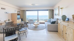 Un salón moderno con comedor, un sofá, un televisor y vista al mar.