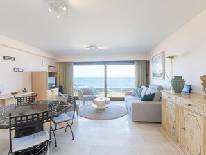 Ein modernes Wohnzimmer mit Essbereich, einer Couch, einem Fernseher und Blick auf das Meer.
