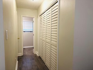 A narrow hallway with a door leading to a room with a window.
