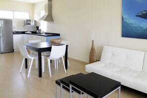 A modern kitchen with white cabinets, a black countertop, and a stainless steel refrigerator. - Dolphin Suites (Willemstad)