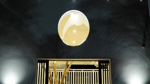 A spherical light fixture centered on a dark wall with a window below. - Dolphin Suites (Willemstad)