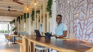Un espace bar doté de comptoirs en bois, de luminaires suspendus en osier et d’un design moderne avec un motif d’arbre sur un mur.