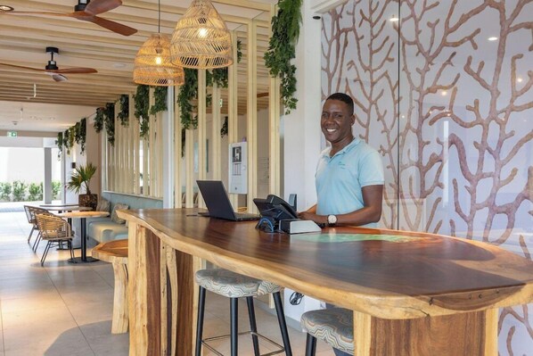 A bar area with wooden bar tops, hanging wicker lights, and a modern design with a tree pattern wall. - Dolphin Suites (Willemstad)
