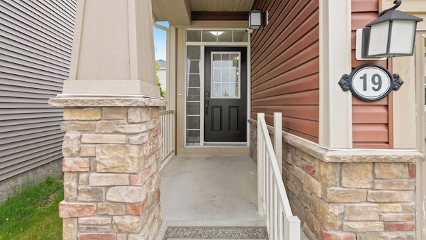 A house entrance with a stone pillar, a black door, and a house number 19. - A Beautiful Home in Airdrie (Airdrie)