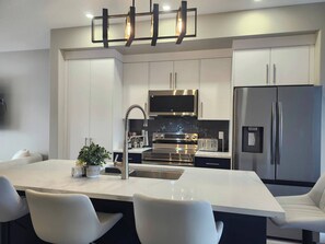 A modern kitchen with a central island, stainless steel appliances, and a minimalist design. - Harmony Haven in Drumheller (Drumheller)