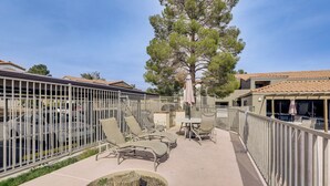 A rooftop patio with outdoor seating, a large tree, and a view of the surrounding buildings.