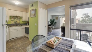 A modern kitchen with white cabinets, a marble backsplash, and a dining area with a glass table and a tray of decorative eggs.