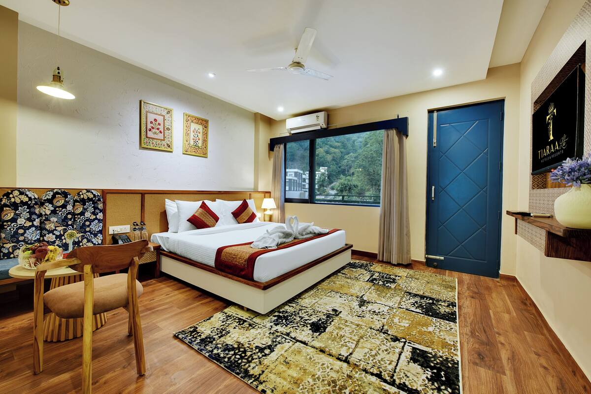 A hotel room with a bed, a desk, a chair, a window, and a door.
