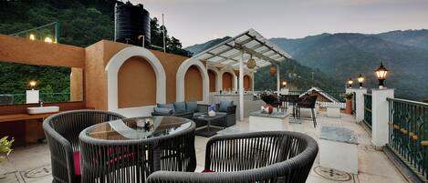 An outdoor patio with wicker furniture, a glass table, and a pergola.