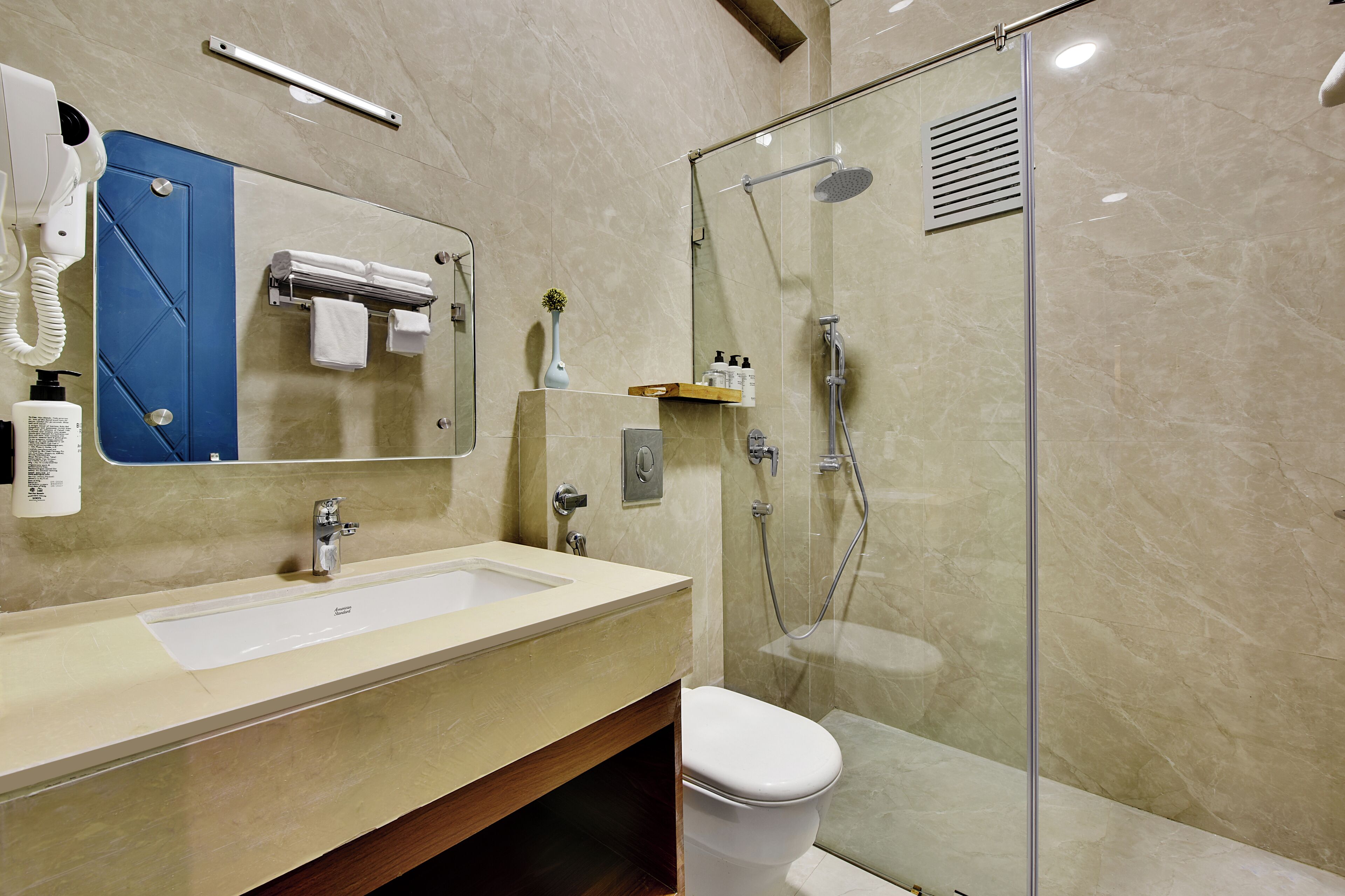 A modern bathroom with a large sink, mirror, and glass shower enclosure.