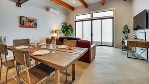 Un comedor con una mesa de madera dispuesta para cuatro personas, un sofá y un escritorio con una computadora.