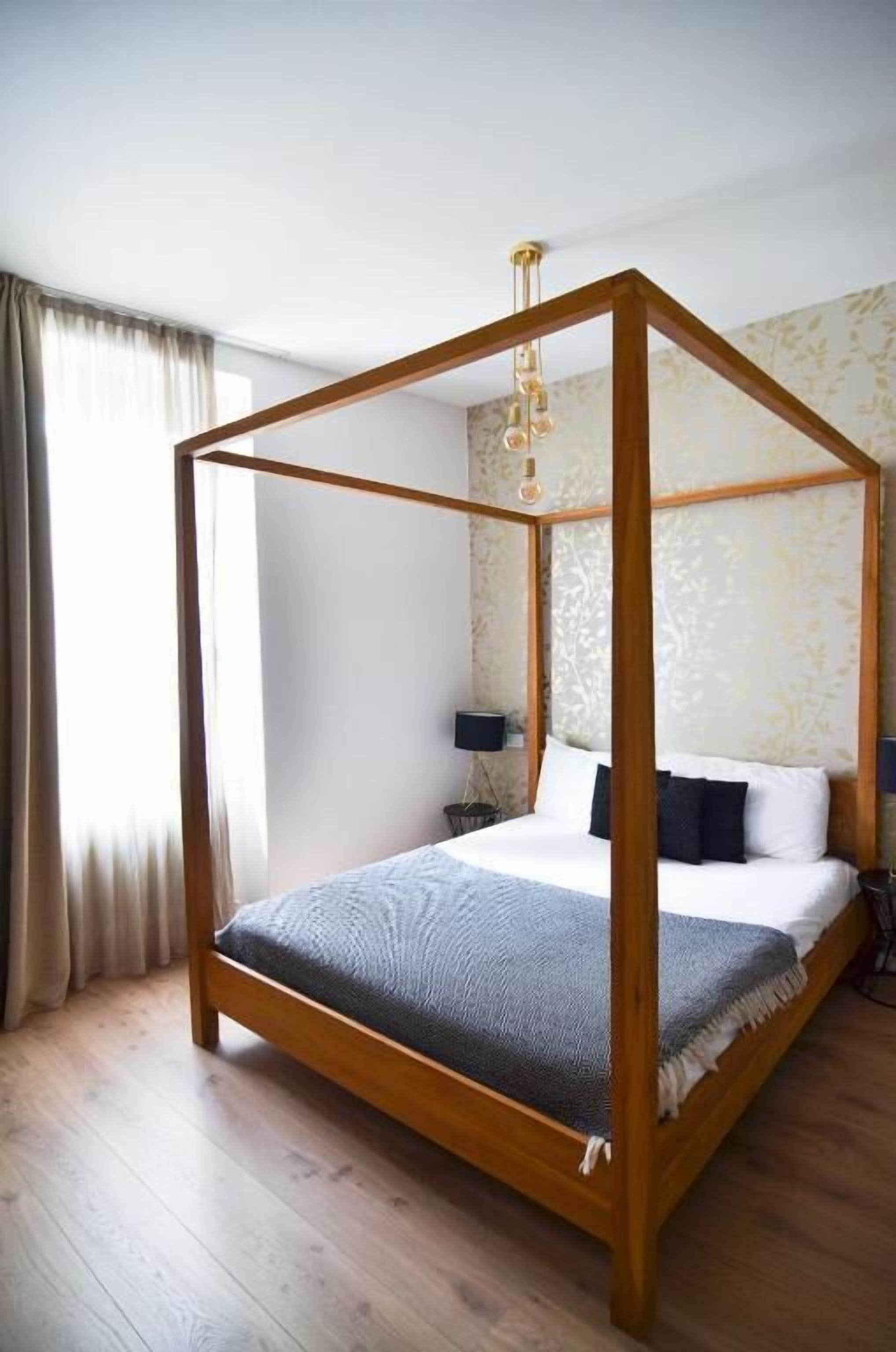 Ein Himmelbett mit Holzgestell, weißer Bettdecke und zwei Kissen.