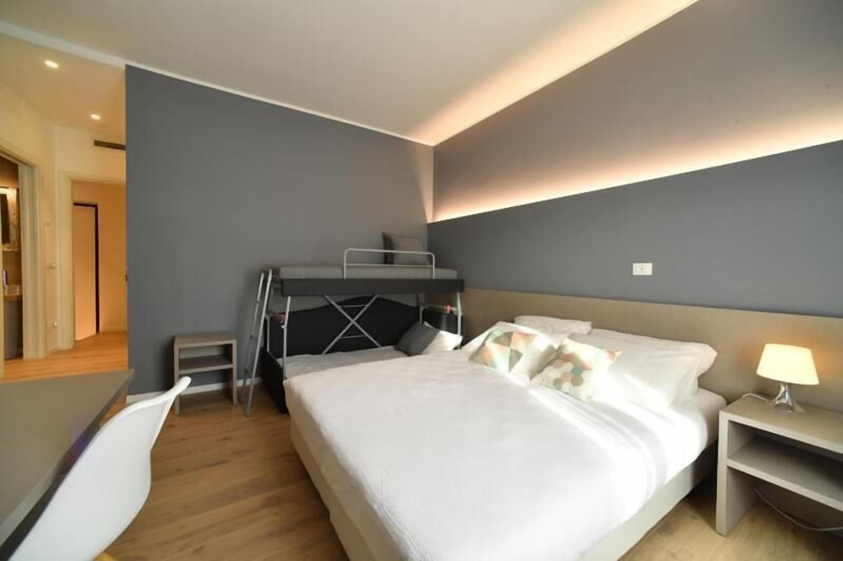 Un dormitorio moderno con una cama litera, un escritorio y una mesita de noche.