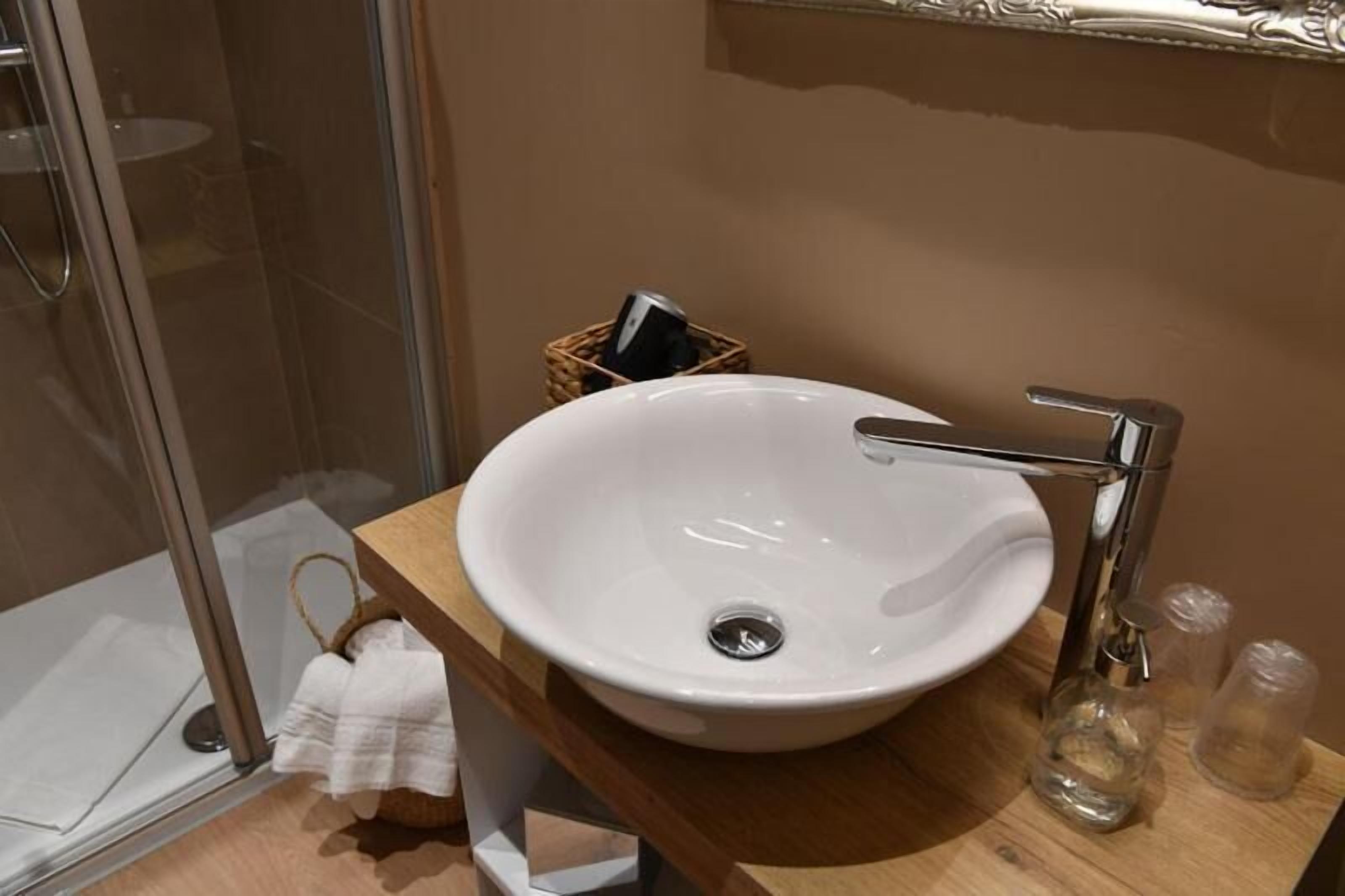 Une salle de bain avec un lavabo blanc, un robinet chromé et un meuble-lavabo en bois.